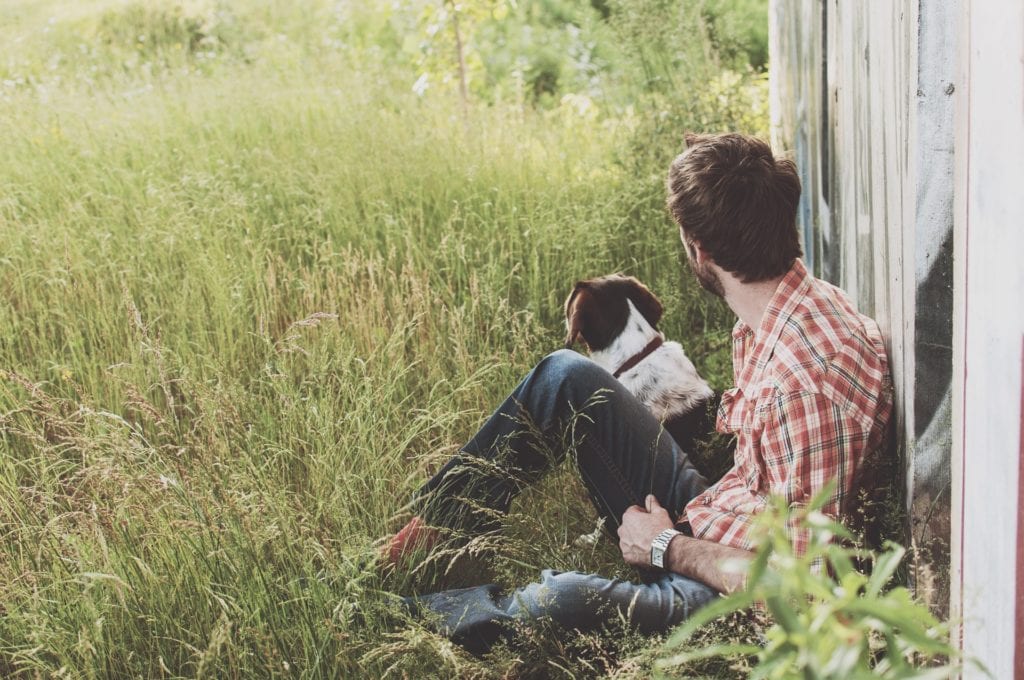 Homme assis dans l'herbe avec son chien